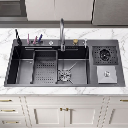 A dark gray double-bowl kitchen sink with a faucet, drain basket, and side storage tray, installed on a white marble countertop above white cabinets.